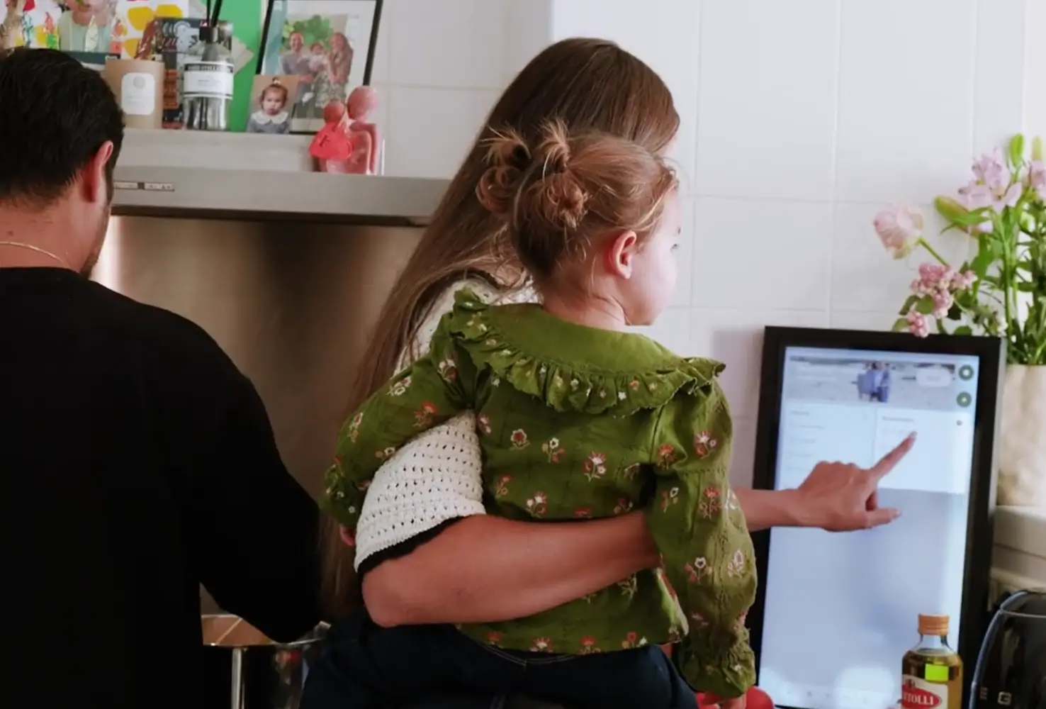 Digitale familieplanner Iemand wijst op digitale familieplanner scherm aan de muur in keuken